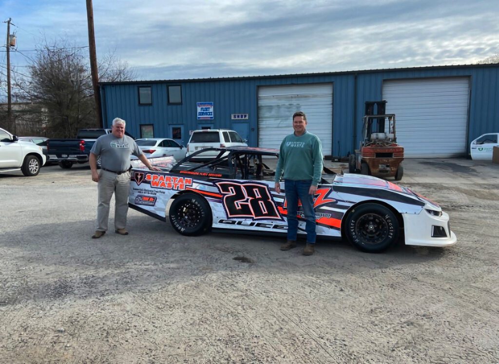 Spartan Waste founders Mark Nelson and Mark Mullen standing by Jeff Queen's race car.